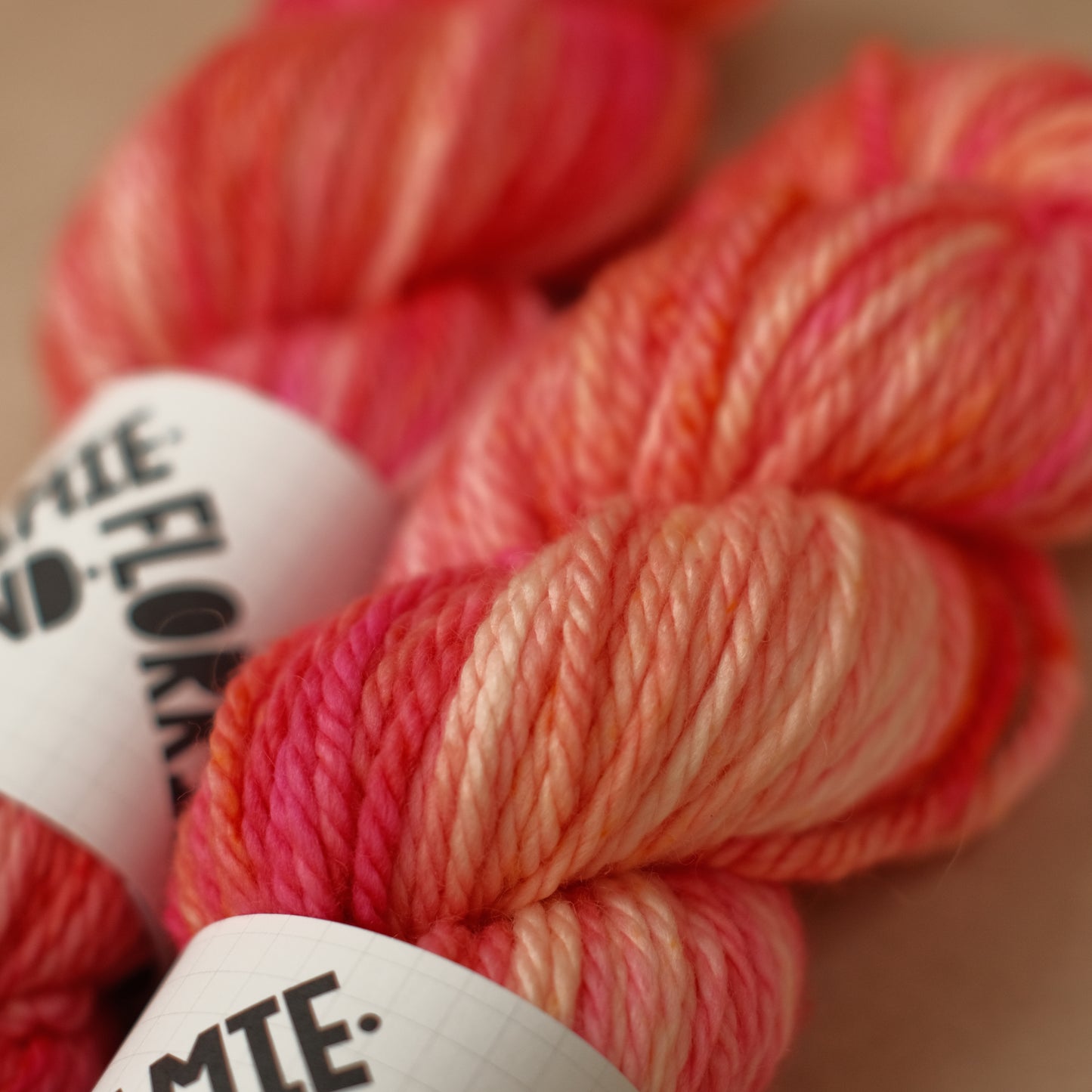 Balls of pink yarn with visible brand labels on a neutral background