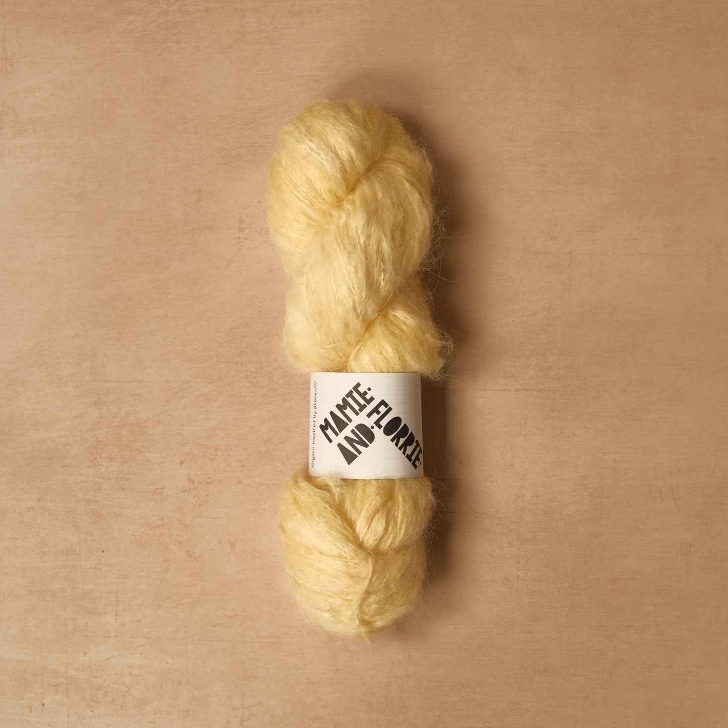 Ball of yellow yarn with a label on a beige background